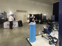 People sitting around tables in the Expo Hall Cafe listening to a presentation