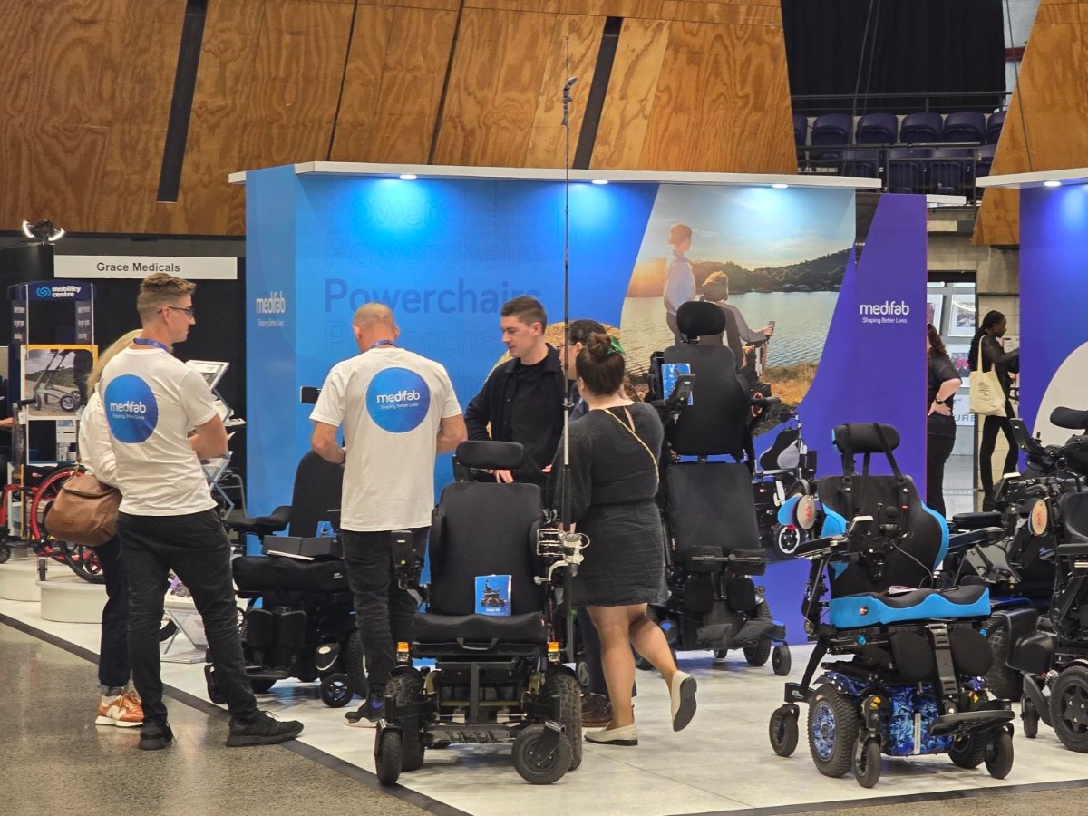 Another Expo Hall view - many powerchairs and attendees in wheelchairs in discussion