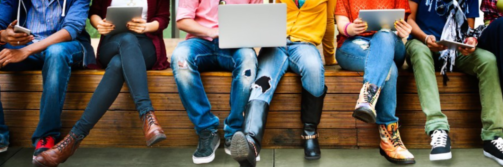 Young adults on bench with laptops