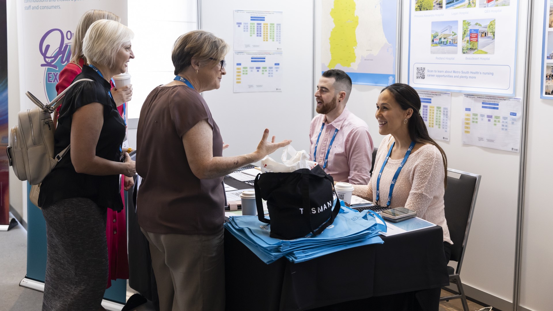 Group of people taking at an exhibition booth.