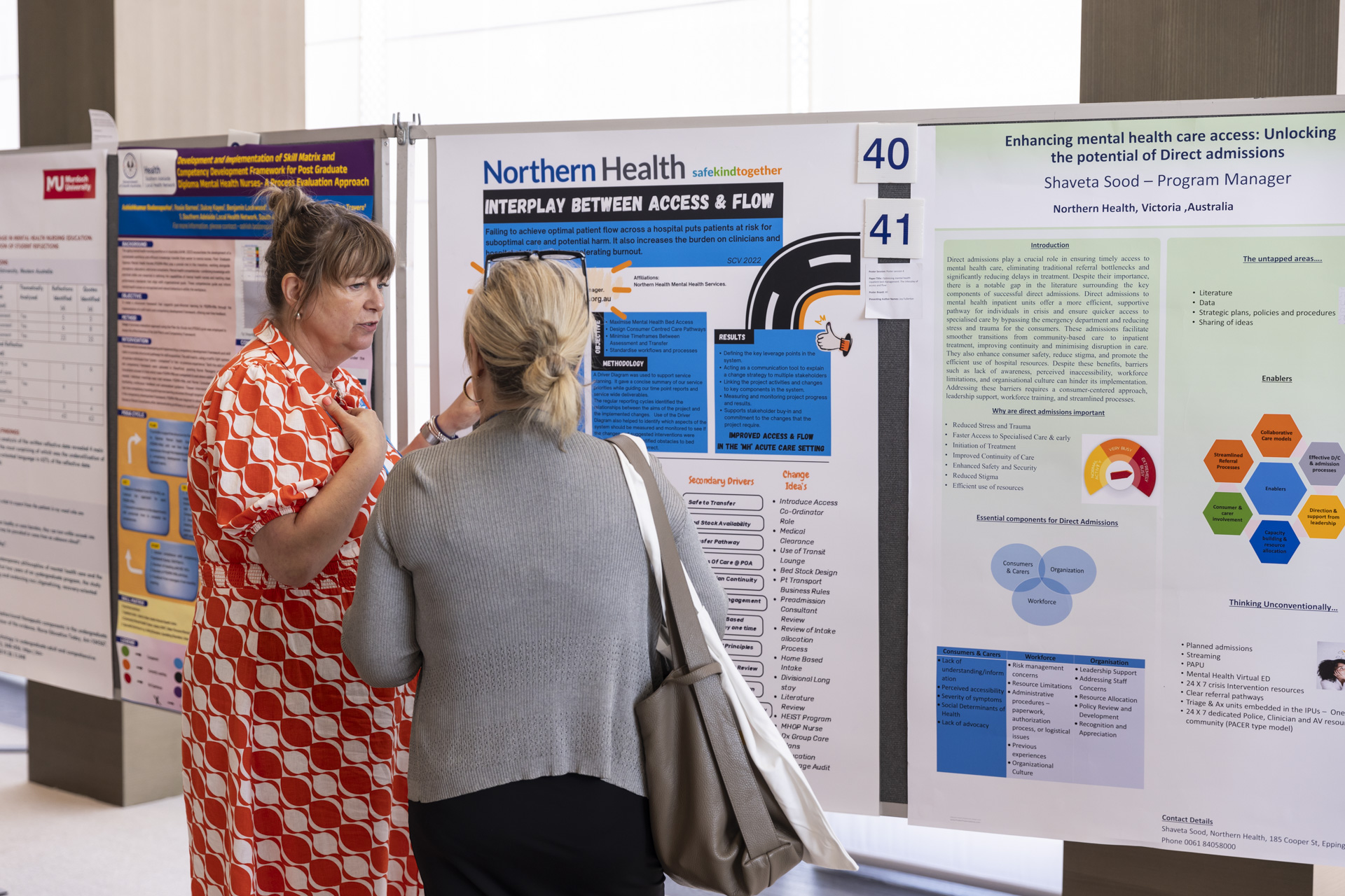 Two people talking in front of a poster.